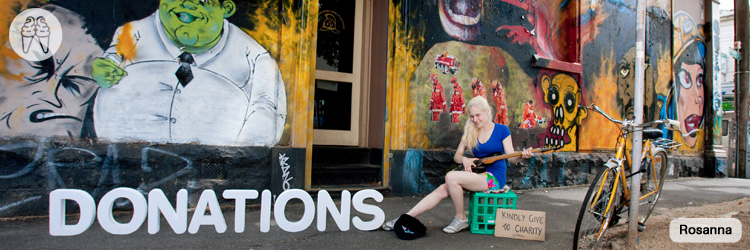 Blonde with curiously unplugged electric guitar busks in the street.